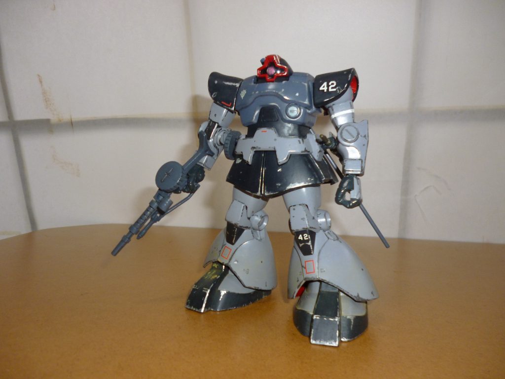 正面素立ちです。
基本カラーは、水性ホビーカラーのニュートラルグレーと、つや消し黒につや消し白を少々混ぜた色になります。
もともとの紫色があまりにも兵器のイメージからかけ離れていたため、08小隊にチラッと登場するドムのカラーリングやリアルタイプカラーをイメージして塗ってみました。
また、足元には黄土色のパステルを削った粉を平筆ではたいて砂ぼこりを、全身には銀色と黒鉄色でハゲチョロを施してあります。
武装も、ジャイアント・バズではなくザクマシンガンを装備させてみました。