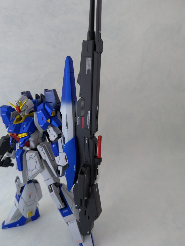 シールドのブルーグラデを真似しようと思ったのがきっかけ。
またハイメガランチャーの中央部にハセガワのフィニッシュシート（赤・カーボンの2種）を使用していますが、これは塗装後に伸縮部の擦れを発見し、再塗装するか考えていたところmat氏のブログ記事にフィニッシュシートを使用したリカバリー案の紹介があったので、それを試してみました。
結果擦れ防止のほか色のアクセントにもなったので、これは今後も活用すると思います。
他にカラーシールもカーボンフィニッシュに置き換えています。マスキングテープの上にカラーシールを貼りシールの大きさにカット、それをカーボンフィニッシュの上に貼ってトリミング…という手順の作業です。
また胸・肩などのレッドポイントもフィニッシュシートを細切りにしたものを貼り付けています。
フィニッシュシートはキット付属のシールより非常に薄く、貼り付けただけでも馴染みが非常にいいです。