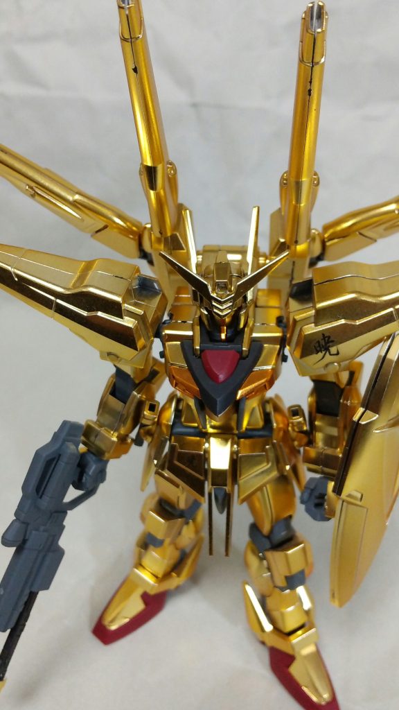 アカツキガンダムの武装は72D5式ビームライフル”ヒャクライ”、73J2式試製双刀型ビームサーベル、試製71式防盾です。
宇宙戦闘専用兵装”シラヌイ”を装備するとシラヌイアカツキガンダムになります。”シラヌイ”にはM531R誘導機動ビーム砲塔システム、いわゆる”ドラグーン”が７基搭載されています。
全身を覆うゴールドのビーム反射装甲”ヤタノカガミ”は、撃ち込まれたビームから機体を保護するだけではなく、本体のセンサーが追尾した敵機に向けて自動的にビームを送り返す、攻防一体のシステムだそうです。
設定を読んでいるだけで心躍る、金ピカのガンダムです。