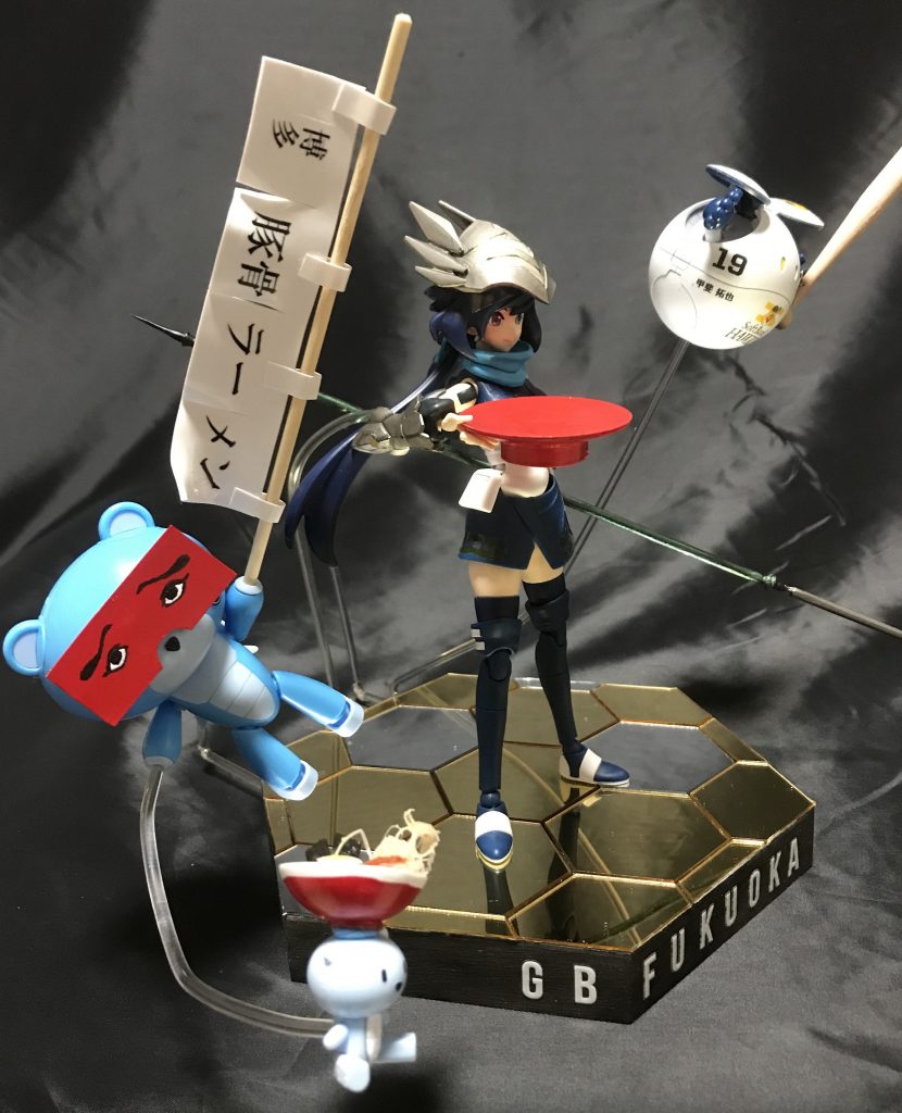 博多にわかのお面をつけラーメン屋の暖簾を装備したプチッガイです。
博多にわかとは「にわか面」という変なお面をつけた行う郷土芸能で時事ネタ等を取り入れて行う漫才の様な笑劇です。
ガンダムベース限定品のみを使用した作品なので台座にGBといれています。