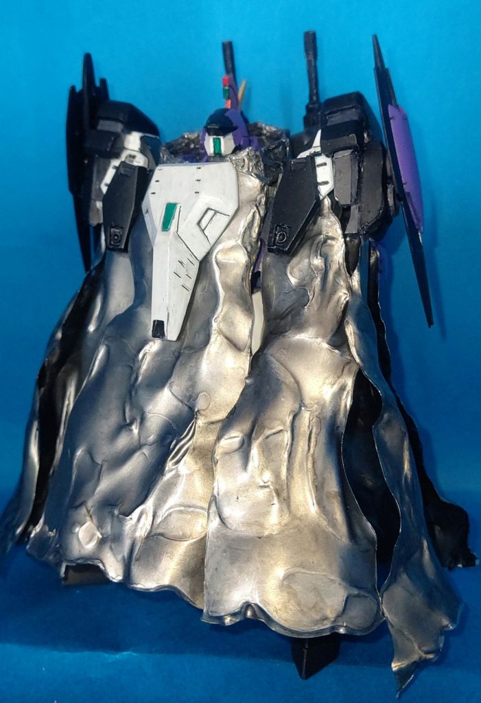 離れた距離を維持して攻撃されることへの対抗手段として、大型ブースターユニット兼アーマーユニットを装備可能です。
アーマーの一部としてマントを採用したのもモデル機へのリスペクトゆえということで。
マントは(プラ板を買ったことがなかったので)クリアファイルを熱して加工しました。