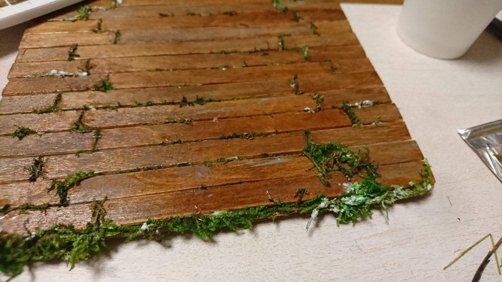 一気に進みます!全てぬれたら上からダイソーの水性ニスを塗ります。
水性ニスを塗る前に水色や白で薄く汚れを描くとそれっぽく見えます♪
ニスがかわいたらダイソーのグリーンモスをボンドとあえてマドラーの間に埋め込んでいきます♪
生えてる感じを再現!w