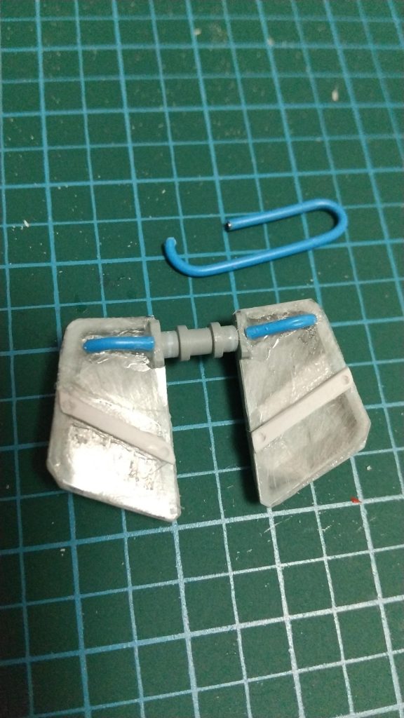 アーマーの形に切ったロキソニンのシートを貼り、その上に『ランナーを削って作った棒』と『ゼムクリップを切ったもの』を貼りました。
棒にはピンバイスで穴を開けてみました。

プラモデル用の接着剤では接着できませんので、瞬間接着剤を使います。
塗装が食いつくようにロキソニンの表面はやすりで荒くしています。

前部アーマーには四角い箱が付いていますが、これは現在の設定では「ヘリウムコア」とか言うものでまぁ何か入っている訳です。ですのでアーマー裏というかアーマー内部には四角い箱から本体への供給用にパイプとかあるはずで、模型の表現として、それを出して見せた方が説得力あるかな、と思った次第。
ガンプラ的にはザクの動力パイプを使えば良かったかもですが、余剰の動力パイプは持ってないので、クリップを使ってみました。