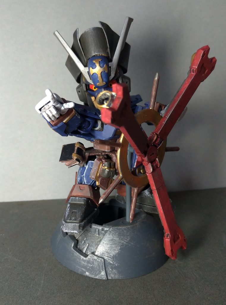 バックパックはスラスター部分を三本に無理やり変更し、舵輪型パーツを新造。付け根ごと移植したので可動もOK。
無理をこさえたので、ちょっと強度は不安ですが、ザクヘッドの余りパーツを使用して舵のように据え置けるようにしました。