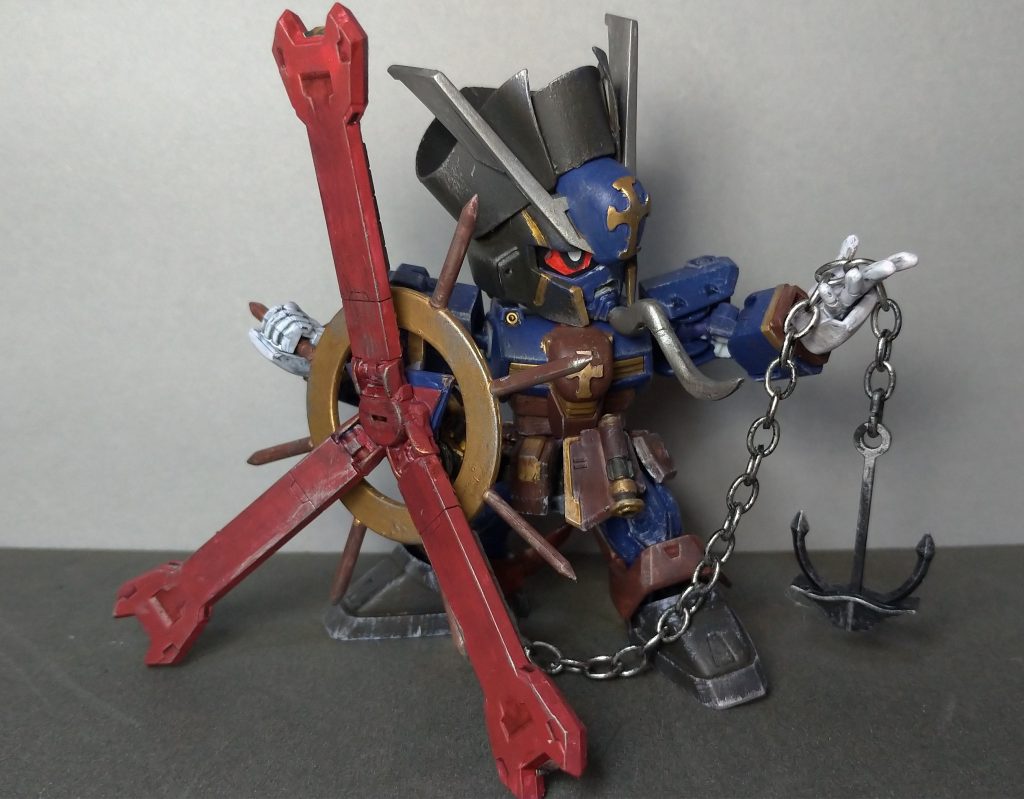 ●バスターハンドル(背部スラスター)
レジスタンスガンダム専用武器。
舵輪を模したスラスターユニットに、
大型のアンカーが装備されており、
その重量によって打撃する武装。