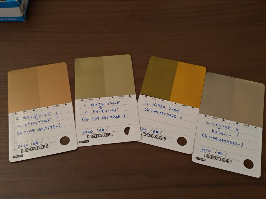 塗装に使ったゴールド塗料について。
パーツの成型色ごとにゴールドの塗り分けを行いました。
白部…ガイア・EXゴールド+EXシルバー…4:1
赤部…クレオス・GXレッドゴールド+ガイア・ヴィクトリーブラウンゴールド…3:1
青部…クレオス・GXブルーゴールド→クレオス・トパーズゴールド
黄部…ガイア・ヴィクトリーゴールド
(以上すべて下地は黒サフから塗装)
その他塗料は以下の通り。
フレーム…ガイア・メカサフ ライト
黒…ガイア・メタリックブラック(2020年ガイア福袋同梱品)
メインカメラ・ツインアイ等…スターブライトジュラルミン→蛍光ブルーグリーン
GFハンドパーツ…ガイア・パールゴールド
トップコード…ガイア・EX蛍光クリアー
今回ゴールドの調色をいくつか行ったことで学んだことがありまして、
”青系のゴールドは調色よりクリアーカラーやパールカラーでのレイヤリングのほうが良い”なぜかというと青系ゴールドを調色で作ろうとすると「ゴールド+ブルー=緑系ゴールド」に変化してしまうから。勿論どのような色合いを求めているかによりますが、少量ずつクリアーorパールカラーを重ね塗りして理想の色合いを作るほうが良いと思います。
デカールも貼り付けしようと思ったのですが「元カラーがトリコロールなのにゴールドに変化したらコーションマーク類はどんな色に変わる?デカールもゴールドになってしまったらアクセントにもならないのでは?」等と変な方向に考えが向いてしまったので今回はデカールなしに。