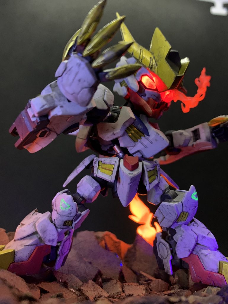 メイン画像加工なし。
ダインスレイヴ後の左腕欠損状態をメインにしようと思ってたのですが、この写真がすごく良かったのでこっちにしちゃいました。
## 塗装
主にアクリジョン、一部水性ホビーカラー使用しました。サフなしです。
以下Aがアクリジョン 、Hが水性ホビーカラー
白: Aベースホワイト+白+明灰白色少量
赤: Aベースレッド→Aモンザレッド
黄: Hシルバー→Aクリアイエロー
青: Hシルバー→A青+モンザレッド少し
グレー: A焼鉄色+ベースグレー+ジャーマングレー
目の周り: Aブラック
眼光エフェクト: A蛍光レッド→Aクリアレッド
緑のツインアイ: ガンダムマーカー蛍光グリーン
ガンダムフレームの部分塗装にHシルバー、Hカッパーを筆塗り
膝とテイルブレードのマークをA蛍光グリーン
## ウェザリング
全体に入れた傷を水性ホビーカラーのシルバーで塗装。
アクリジョン焼鉄色でエッジをドライブラシ。
Mr. ウェザリングカラーでウォッシング。薄めたマルチブラックを全体に、グレィッシュブラウン、サンディウォッシュ、マルチブラック、マルチグレーでピンポイントに汚し。うすめ液をつけた綿棒で拭き取り。
## 仕上げ
水性ホビーカラーのつや消しクリアーでトップコート。
## 電飾関係