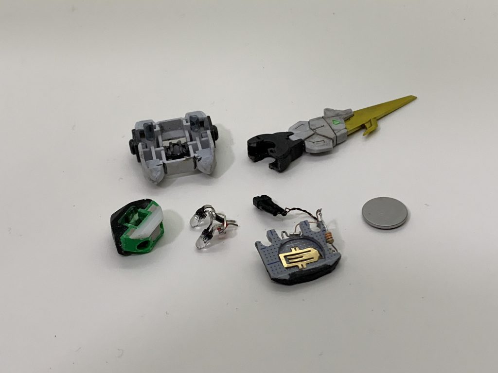 ボタン電池CR1220をバックパックに内蔵。省スペース化のため、電池ボックスをプラ板で自作してます。
テイルブレードの付け根をスイッチにしてあり、テイルブレードを持ち上げると点灯します
https://twitter.com/sawat1203/status/1253359326103662593?s=21
ツインアイ の部分はUVレジンに置き換えています。
## ベース
今回、初めてベース制作に挑戦しました。