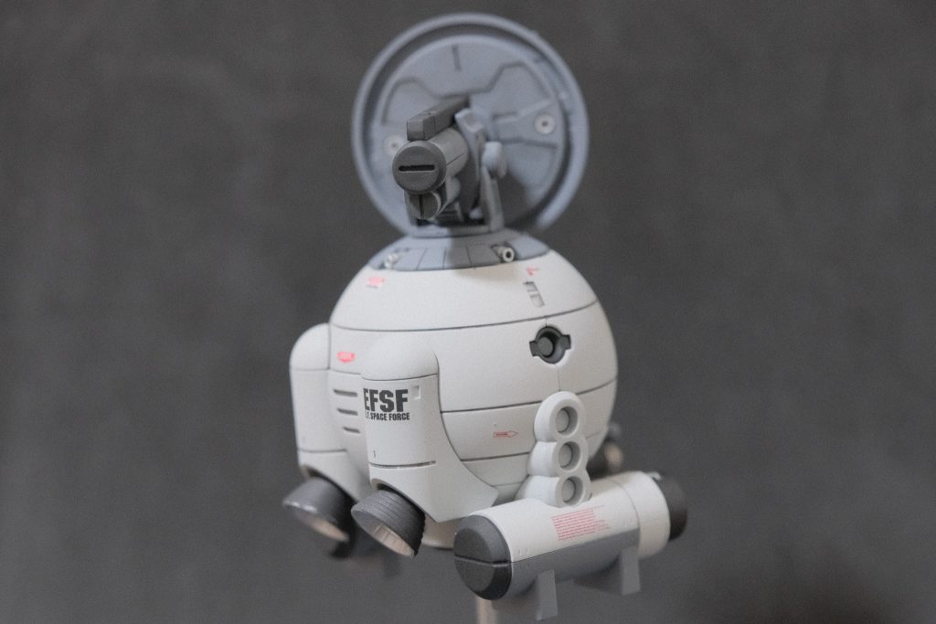 高濃度ミノフスキー粒子はレーダー波を妨害する一方で可視光は大きな影響を受けない。
そこで連邦高官は高性能カメラおよびミノフスキー通信に対応したアンテナを装備する
偵察機を複数配備するプランを発案、これにより開発されたのが当機である。

しかし、後にレビル中将が奪還され、V作戦およびビンソン計画が発令されたことにより
連邦の方針は大きく転換され、当機は少数が生産されるに留まった。