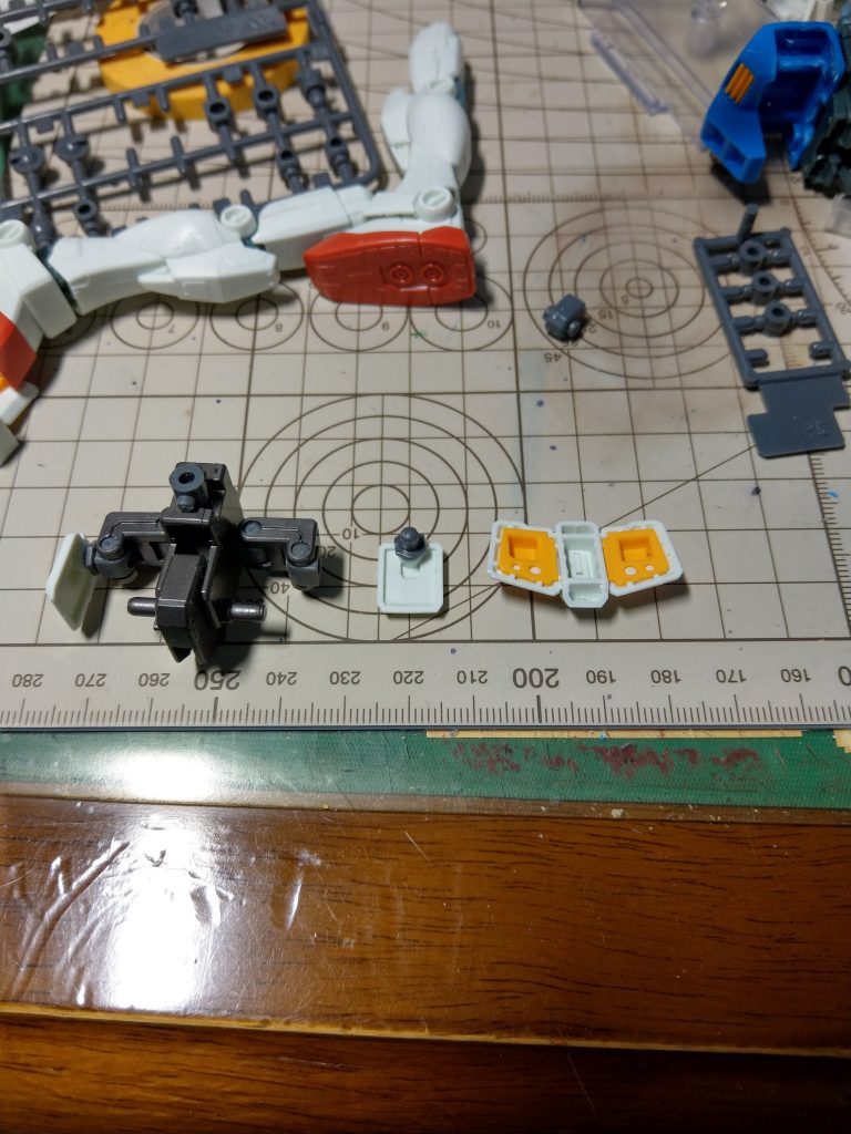 その外側。イージスのリアスカートをつける部分には、同キットに入っているPC20(サイドスカートの受けとかに使うやつ)を使うことで、リアスカートの中央の窪みがすっぽり入ります。本当は接着した方がいいんでしょうけど。
ガンダムのリアスカートは下部の出っ張りを斜めにカットしてあります。これをしないとフロントスカートを下げる機構と干渉するので。twitterの方では無加工で取りつけられると書いてしまいましたが、ご容赦ください。
サイドスカートはまず、L字型のパーツの外側の穴を広げて両方3mm軸用の受けにして、イージスの凸凸(だった気がするもの)で接続。