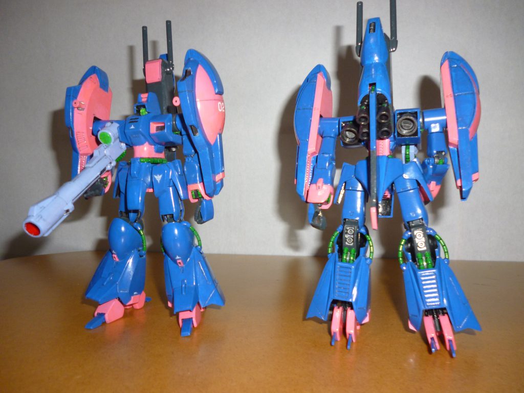 モビルスーツ形態での正面素立ち&リアビューです。
今回の作品は2つのコンセプトの元に製作しました。
まず最初のコンセプトは「毒々しいまでにビビッドなカラーリング」です。
そのため、いつもの自分の地味な作品にはまず使わないような鮮やかな塗料を使用しました。
基本塗装はインディブルー、ピンクの下地に、ワインレッドとピンクを蛍光ピンクの空きビンで混ぜたショッキングピンク、動力パイプのディトナグリーン、ナックルバスターはすみれ色です。
また、モノアイと右胸のセンサーは裏からカッターとタガネでスジボリを入れたHアイズを張り付けてあります。