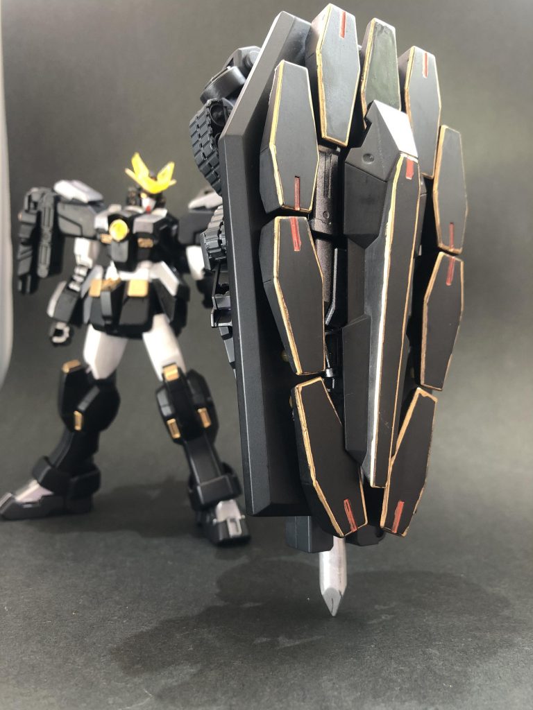 ## ・ゲンブ盾形態[黒曜の大盾]
ゲンブが変形した超重量の巨大な盾。
戦艦のメガ粒子砲を防ぐ程の堅牢さを誇る。
MB時同様ビットを飛ばして広い範囲の防御も可能。
しかし例に漏れず重量多過で取り回しが困難であるため、運用するには専用の装備(後述)が必要。