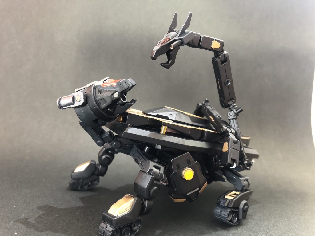 ## 亀＆蛇型MB『ゲンブ』
AI(穏やかな老人モデル)を搭載した、最初に開発に成功したMB(モビルビースト)。
聖獣・玄武(蛇が巻きついた亀の姿)がモデルとなっており、蛇の部分はゲンブのAIがビットを操る要領で動かしている。
口部•背部の砲撃、蛇を分離して偵察、ビットでの防御、大型の盾に変形するなど様々なサポートを行う。

他のMBのように本体との合体強化は想定されていなかったが、後の改修でゲンブ自身が強化形態を得る事となった(詳細は次回)。