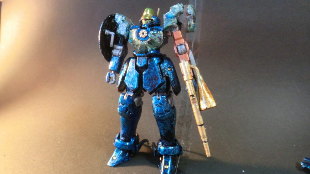 フロント
マグアナック隊に所属するも、突如の敵襲で右肩、左腕を大きく破損。ジャンクパーツで改修し、コックピット部と肩部は特殊な鉱石を含む加工を施し、耐久性を高めている。
襲撃後、散り散りになってしまった自分達の部隊を探す為にライフルに付いているスピーカーからマグアナック隊にいた頃に仲間とよく歌っていた歌を流しながら探し回っている。