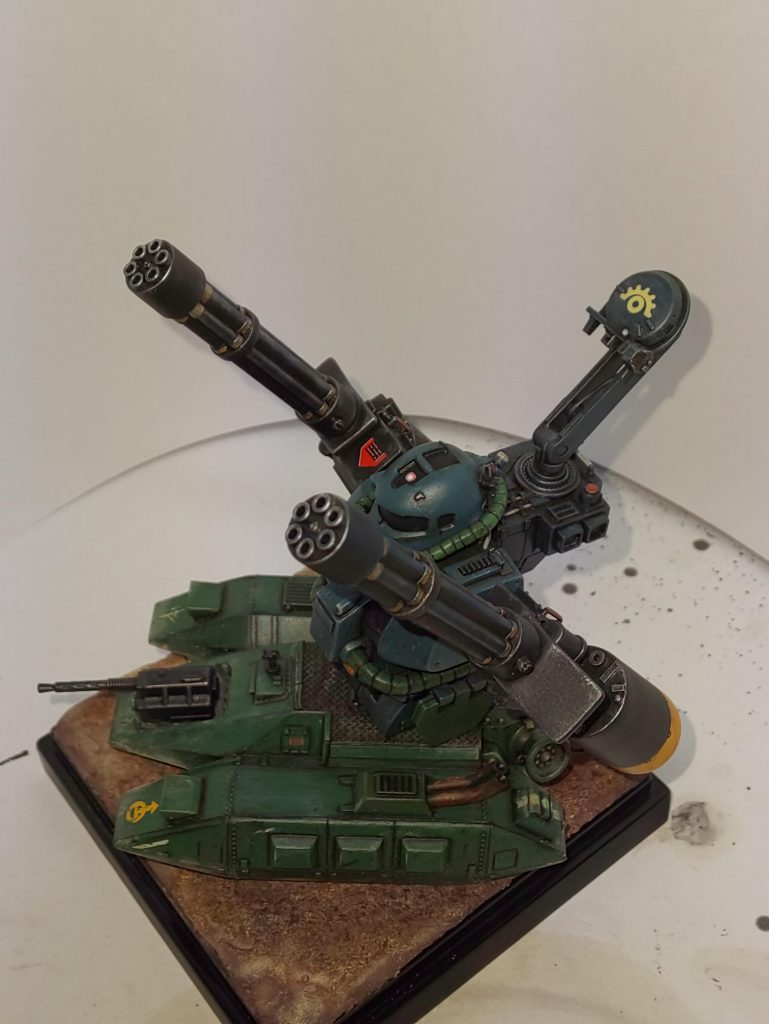 ガトリングはザクの肩パーツをそのまま流用しています。
モノアイは頭頂部まで延長してます。
キットの頭はいつか入手できるであろうザクR型のために温存したいので、ジャンクからモノアイ延長工作もやりやすい部品割りだったので、08シリーズのザク頭を流用しました。
ランドセルは射撃管制システムです。
ミノフスキー粒子がある中でも ある程度の距離ならレーダーが使えるだろうし、光学機器で視認出来るならモノアイと連動すれば射撃密度も上がるかな?