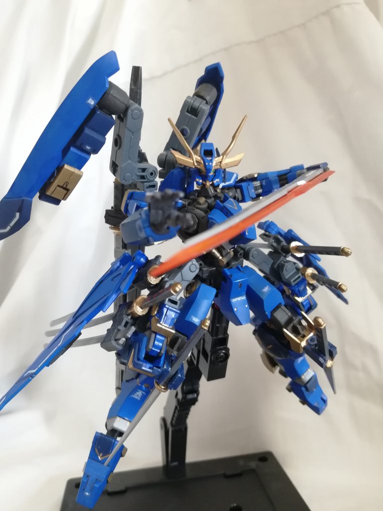 背部中央に装備された大太刀です。画像一枚目の様に、通常の状態では他の装備とは違い刃が無く、殴るか叩きつけるぐらいの用途しかありません。しかし、この装備の真髄は画像二,三枚目の状態にあります。この状態は機体が生成するエネルギーを極限まで刀に送り込むことで、約100秒間(伸ばすことも可能だが使用後機体を数時間使用不可能になる)MAのものより高出力高濃度のビーム刃を形成することができます。これにより敵機のフレームごと溶断したり、MAとの戦闘を優位に進めることもできます。

そして...