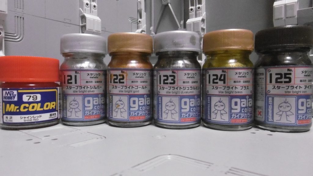 ガイアカラー中心の塗料陣。右５つは前作と共通。配色パターンは元の色との比較でそれぞれ下記のように決めました。
　赤：シャインレッド
　白：スターブライトジュラルミン
　紺：スターブライトアイアン
　黄：スターブライトブラス
　緑：スターブライトゴールド
　刃：スターブライトシルバー

挑戦や失敗なしに理想の物は作れないのだなと実感しました。
接着剤の跡が残っていたり、塗りムラや調整ミスがあったりと粗い部分もあちこちに散見されますが、完璧を目指さず今の自分に可能な最大限の表現が出来て満足です。*発案から完成までに３年以上かかった*のは予想外でしたが、[５年モノの過去作](https://gumpla.jp/hg/343676)に比べれば製作に余裕ありました。

直前まで迷いましたが、たまたま７月中に完成させられたので、
「すえ王」企画に参加します。賑やかし枠になれれば幸いです。
偽者を冠する機体でも、格闘機がベースだからきっと強い。はず。