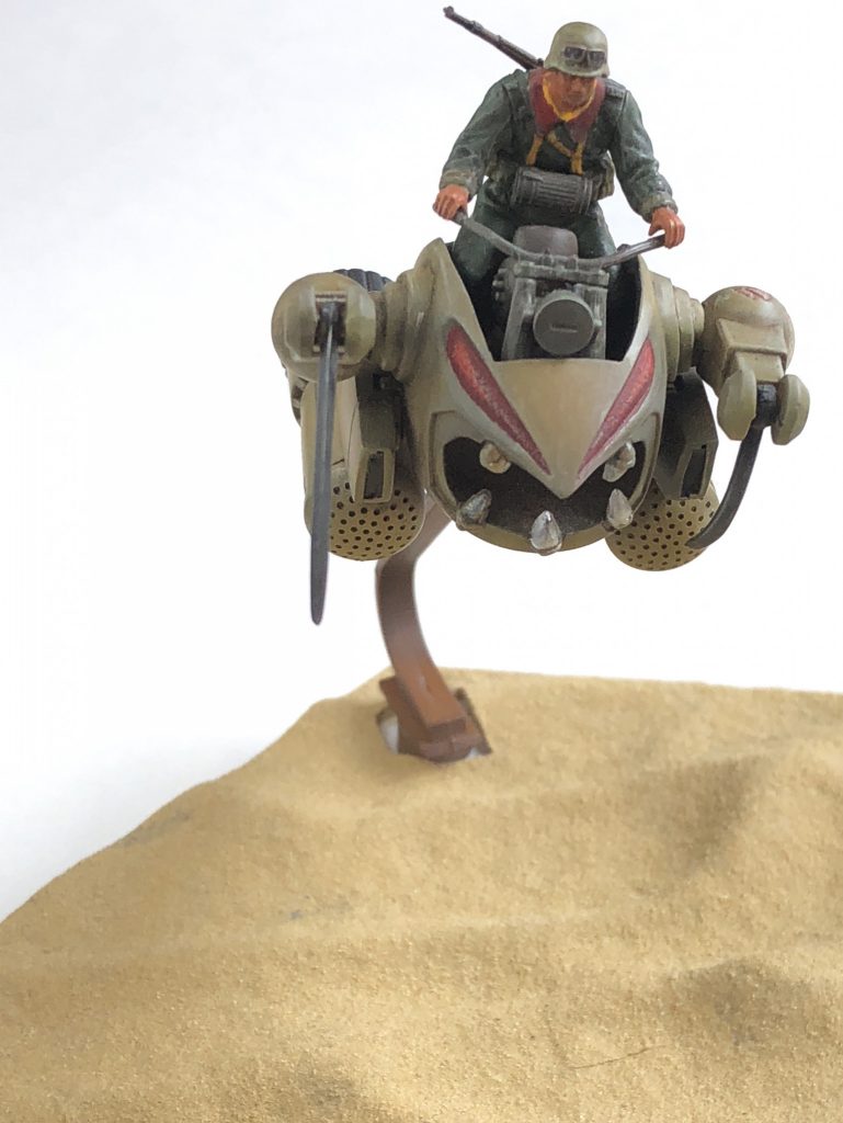 砂漠をモチーフにしています。
ベースは最近発売されたカスタマイズシーンベースを使用。
情景テクスチャペイントを筆で塗りつけています。

ザクレロのカラーリングはオリジナルです。
下地マホガニーサフにダークイエローを
グラデ塗装したのですが、その後のウェザリングで
殆どわからなくなりました。

跨がる人間は確かドイツ兵だったかな？？
設定資料見ながらジオン兵風に筆塗りで塗装しています。