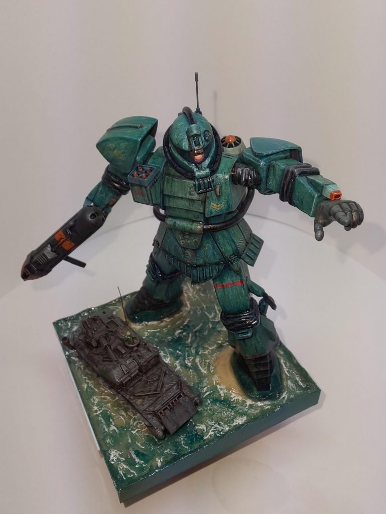 冗談はさておき、この水ザクは8割り方出来てたのですが、水の表現に四苦八苦しまして、これ以上いじくり回すと収拾がつかなくなりそうだったので このあたりでやめときました。

初めての水景製作でレジンとか使って無いのから こんなもんかなぁ？

水表現は、粘土で波形を作り色を塗って、リキテックスのグロスポリマーメディウムのハードなやつでさらに波を盛って、同じくリキテックスのジェッソで白波をちょんちょん塗って、ウェザリングカラーのウェットクリアを塗りたくりました。