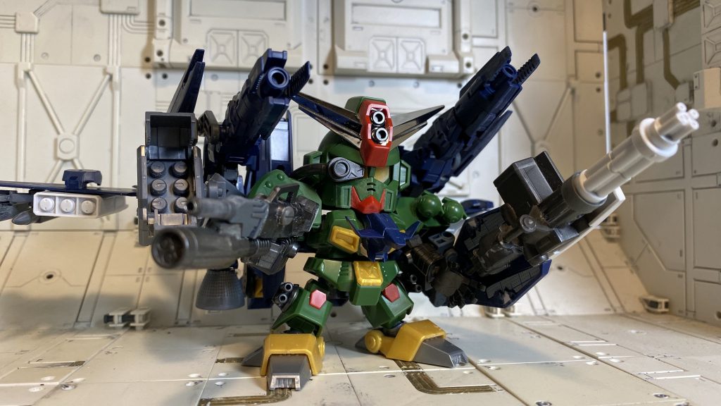 今回はコマンドガンダム本体は大きく手を加えず、合体形態とサポートメカをかっこよくまとめることに集中してみました。
*■本体の工作*
・額のバルカン砲に金属パイプを埋め込み。
・空戦用アルトのパーツを胸部装甲、バックパックとして追加。
・肩にスラスターやディテールを追加、リベットを六角ボルトパーツに置き換え。
・腕が肩パーツから抜けやすいので、深く刺さるようにボールジョイントの受けを加工。
・手首パーツの肉抜き穴をパテで埋め整形、テンションが上がってサムズアップ手首をパテの塊から自作。考えてみればVサインにすればよかった。
・足裏の肉抜き穴を埋めてスリット入りプラ板やスジボリでディテールを追加。
・ライフルはジャンクパーツとレーザーマシンガンを組み合わせて制作。