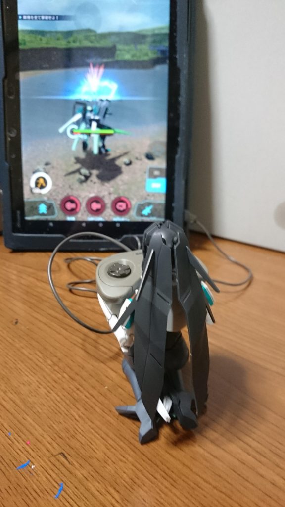 おまけ。メイ「コントローラのサイズがまるで違う…」ウォドムポッドはメイちゃんがコントローラで操作してる事が判明したっスね。というわけで、セガサターンのプラモからコントローラパッドを拝借して、メイちゃんにガンダムブレイカーモバイルをプレイしてもらうっス!コントローラパッドから伸びてるコードはタブレットのカバーに挟んで引っ掛けてるだけっスね。ちなみに画像のタブレットに映ってるのはガンブレモバイルのスクショ。画面の自機は自分が実際にガンブレモバイルで使用しているメイカラーの改造ガンプラっス(⬅メイのスキンを買う勇気はなかった)