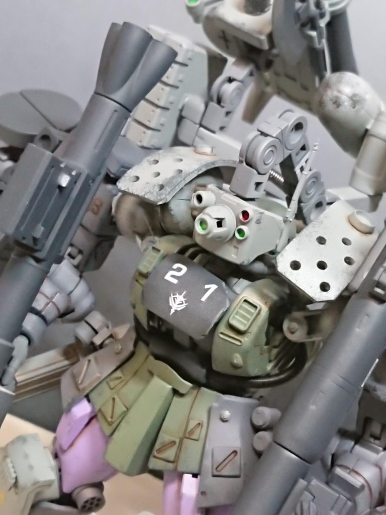 頭部バイザーユニットバックパックからアームを介してモノアイとリンクし、頭部を守る装甲となりつつ射撃精度向上を行う。