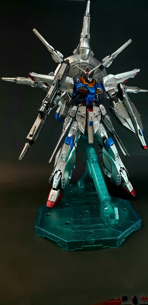 武装　MMI-GAU2 ピクウス76mm近接防御用機関砲頭部及び肩部に装備された対空迎撃用機関砲。MA-M221 ユーディキウム・ビームライフル肩掛け式の大型ビームライフル。ドレッドノートのMA-M22Yを大型高出力化した改良型[13]で、系列機のジャスティスやフリーダムのMA-M20より2世代、ゲイツのMA-M21Gより1世代新型である。大型のために取り回しにはやや難があるが、フリーダムガンダムのMA-M20ルプスビームライフルを上回る出力をもつ[4][注 5]。ユーディキウムはラテン語で「審判」の意。2017年に発売されたマスターグレード(MG)のプラモデルでは、銃身先端からグリップにかけた機関部がルプスと共通であるという解釈がなされ、この部分は先行発売された「MG フリーダムガンダムVer.2.0」の金型を流用している（機体の内部フレームの一部も同様）。