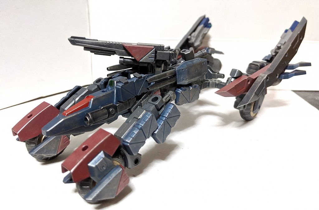 「武装は車体上部に取り付けられたバスターキャノンと左右に取り付けられた2連装ビームキャノン、最低限の武装で構成されており、火力が必要な際にはハードポイントを使用して追加の武装を取り付ける必要がある、またバスターキャノンは戦車の主砲のように上下左右に可動させることができ、下部にはスコープユニットが装備されており、これにより正確な精密射撃を行う事ができる、また車輪部を可動させる事により車体を上下に動かす事ができ、車体が上がっているこの状態が基本的に戦闘モードとなっているが、車体が下がっている状態でも戦闘を行う事は可能である。」キャノン砲もキャンペーンで配布された武器パーツなどを使用して制作、取り付け方法もマシンライダーの下部に付いているジョイントを使用してます。