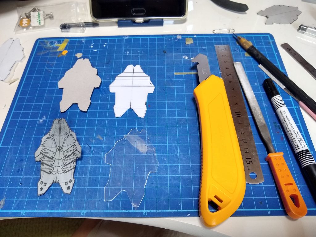 設定資料のデザイン画を変形・反転して型紙を作ってプラ版に薄い折り筋を掘って、薄いプラ版で補強しました。