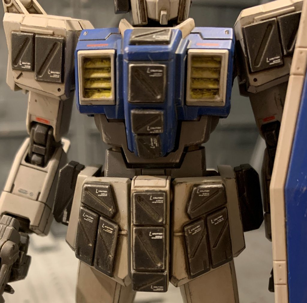 爆発反応装甲は敵MSのバズーカ弾、敵戦車のHEAT弾やAPFSDS弾、歩兵からのロケット弾に有効な装甲材です。腰から上の各所に配置され、脚部には装着していません。原則脚部は露出しないよう立ち回るのと、移動中は脚部は大きく動くので被弾率が低い為です。さらに被弾した際に脚部に装着した装甲が爆発するとバランスを大きく崩してしまい、最悪転倒してしまうというデメリットもある為、現地部隊の中には脚部への爆発反応装甲の装着は禁じている部隊もありました。（ジムストは公式設定で普通に脚部に着けているので、あくまで妄想オラ設定です。)同系列の陸戦型MSでは、スレイヴレイスの肩部にも同様の改修が施されています。腰部フロントアーマーはジムストライカーの物を流用しています。形はそっくりで、小加工で付きました。その他はジムストのデザインに近かったコトブキヤのパネル部品を付けています。