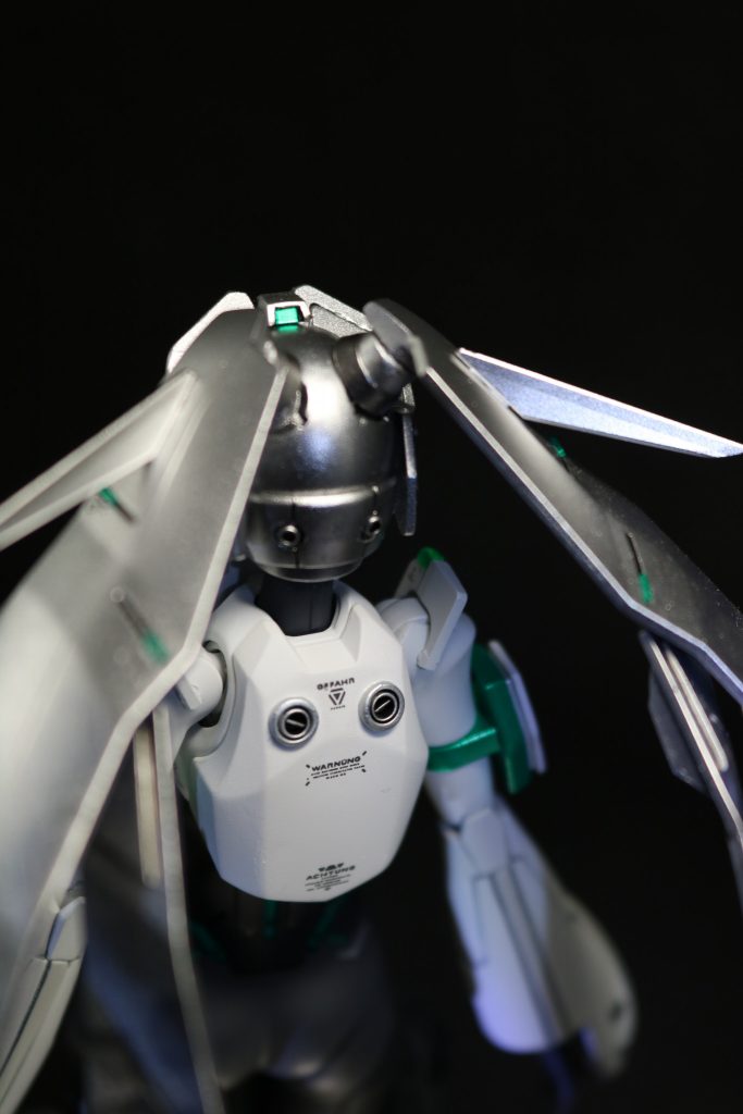 設定画の頭頂部リアカメラがカッコよかったので、再現したかったのですが、キットのままだと範囲が狭く難しかったのでトサカを追加してリアカメラを設置してみました。髪はBJ接続に変更。髪と首のBJが丸見えだったので、隠す為のパーツを追加しました。後頭部には外部接続用のケーブルコネクタを、バックパックには緊急パージ用の爆砕ボルトを追加しました。