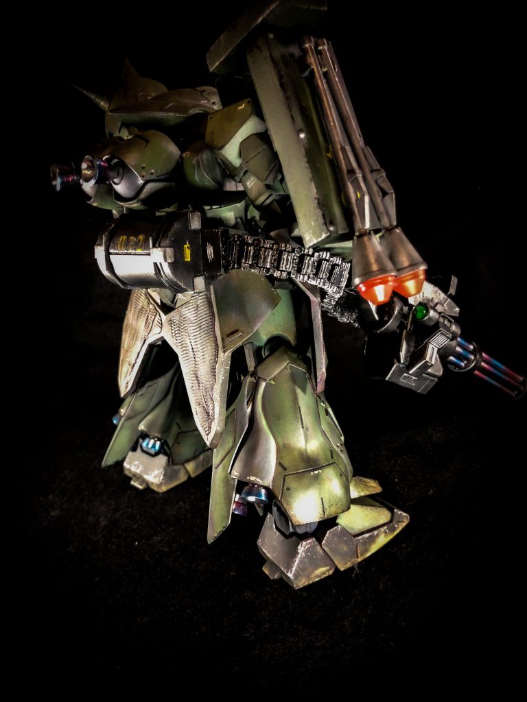 バックショット②背部スカートにマルチウェポンラックを増設。様々な武装等を懸架できる。同様に右肩のシールドも兼マルチウェポンラックとして運用可能である。その姿は往年の名機MS06ザクⅡを思わせる。