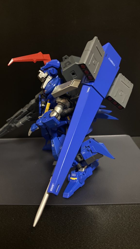 シールドユニット左肩に接続されたユニット。ミサイルポットを担架している他、ブースターユニットとしての機能もあり、先端部にはパイルバンカーが装備された複合兵装である。複数のロックオンを可能とするミサイルは、非常に誘導性能が高く、ミサイル自体に飛行性能を持たせている為、高い命中精度を誇る。また、パイルバンカーの一撃は地割れすら引き起こし、複数のMSをまとめて葬り去る。