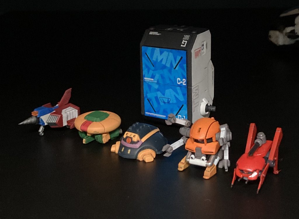 コンテナのTMN迷彩のオサレ具合がお気に入り。マスキングを重ねています。左から、・ドリルファイター（プラモ狂四郎より。RGコアファイターほぼそのまま）・アッシマー（1/220のオマケ。ビームライフルはスクラッチ）・バウンドドック（BB戦士のオマケ。コンテナに入るように幅詰め）・ザクヘッド（ダブルフェイクより　HGUCザクⅡとBB戦士ガンキャノンのオマケロボット、キャンペーン品のプチモビを元にスクラッチ）・モビルビット（ダブルフェイクより　ザクⅢの頭以外はほぼプラ板とパテのスクラッチ。虫嫌いの私は製作中から顔が引きつってました。本邦初立体化？）そのほか、軽装モードや、各サポートメカ（ほんとはプチモビと呼びたい）の個別画像はツイッターを参照してください。ありがとうございました！！ 