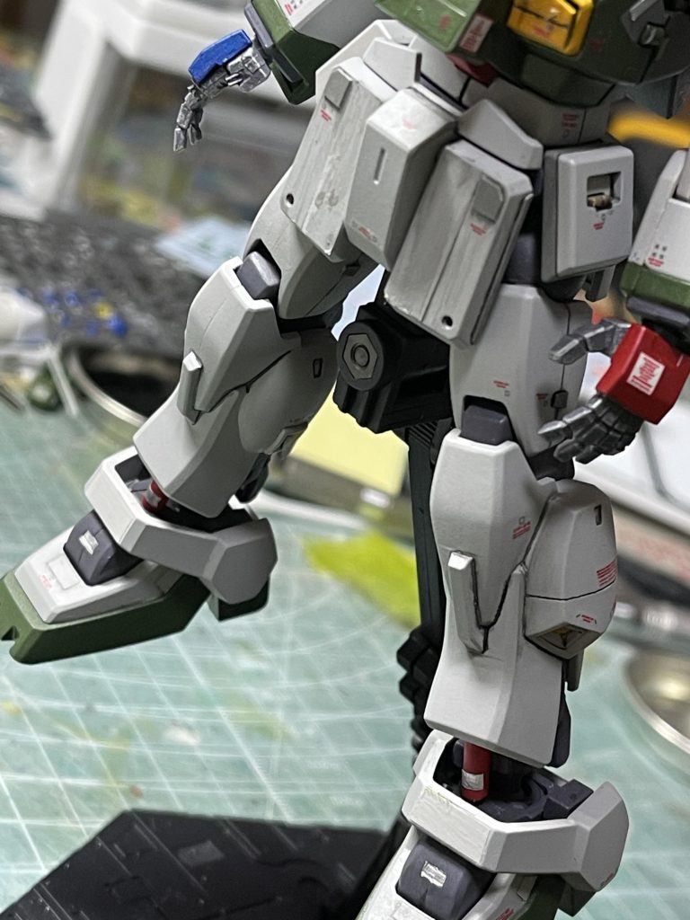 「前から聞きたかったんですけど班長、なんでND02ってMK2の脚なんスか？ネモの純正パーツ使えないし、古いし規格外の物が多くて整備大変なんスよねぇ」「ネモは確かに現行機でMK2は旧型で規格外の『ガンダム』だ。だが流石旧型でも『ガンダム』だ。部品精度、サスの自由度、ダンパー容量などは現行機の脚廻りより断然良い。単体MSで見ればオーバースペックだが、彩雲はこんな重いの背負ってるんだ。これぐらい奢ってやっても足らんぐらいだ」　脚はガンダムMK２のものを使用。スジボリで外装をパージできるような分割ラインを入れてあります。流石に0088年時からはパーツ単位のアップデートがなされているはず。足回りに関しては、新車セダンの簡素化された物より旧車レーシングカーの足回りのほうが性能が高いなんてことはまま有ることで。班長はこういう観点からMK２のものに換装したと考えます。オリジナルMK２の足首はツインショックですが、この部分は現行品の大容量モノショックに交換している、というマニアックな設定有り。　手の甲が左右派手な色ですが、航空機の翼端識別灯と同じ意味です。空母に着艦する際は腕をおおきく開いて機体幅をクルーに分かりやすく、とか。 