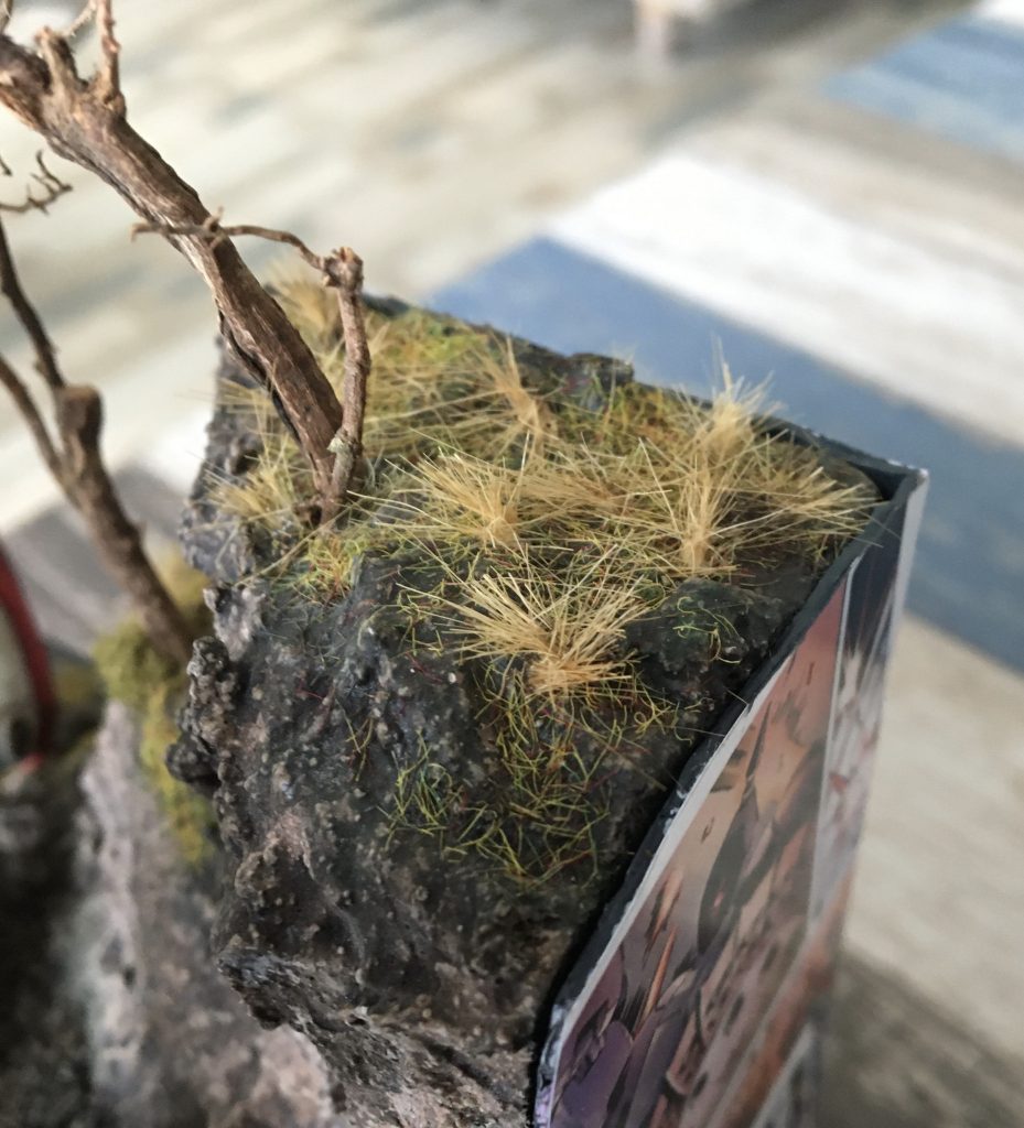 崖はスチレンボードで造形しブラスターを塗布してます。木は本物の根、草はスタティックグラスを使用しています。崖があることでベースに高低差と荒れた土地の感じが出たような。