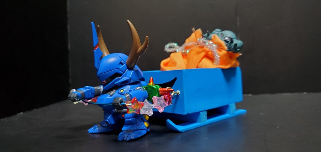 ハイゴッグソリ。プラ板と木材を加工して製作しています。オレンジのプレゼント袋はブースターのイメージ、ヒモはケンプファーのチェーンマインをイメージしています。ズゴックEはプレゼントのオモチャです。