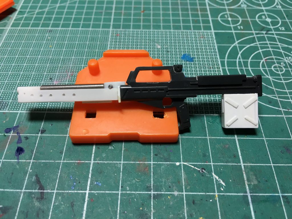 芯が出来たら銃身には1mm穴を5つ開けたプラ板を接着。ライフル本体は銃身の上部を一部切り欠き、突起がかみ合うデザインを再現しました。弾倉は細切りのプラ板で設定のディテールを追加。 製作に当たっては10年ほど前にホビージャパンで発表された、ジム・キャノンⅡの作例での写真を参考にしました(月刊ホビージャパン2011年8月号)。本家のデザインと比較して頂くと分かるかもしれないですが、バイポッドなど一部ディテールを省略しています。 塗装はほぼガンダムマーカーです。アドバンスド・ヘイズル、ヘイズル2号機とティターンズカラーの機体はもう3体目になるので、塗り分けパターンには頭を悩ませました。青=ガンダムマーカー ガンダムブルー本体部グレー=同グレージム・ライフルのグレー=Mr.カラースプレー ニュートラルグレージム・ライフルのグレー2=ガンダムマーカー ガンダムメカグレー黄=同イエロー黒=同ブラック 今回は指の塗り分けが無くて楽だった…。