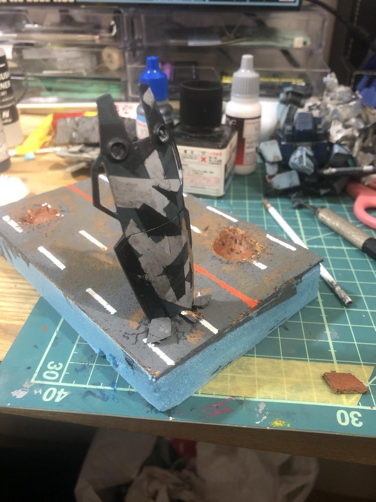 道路は百均のコルクシートに情景テクスチャのダークグレーを塗っています。カッターでくり抜いた後、くり抜いた部分を瓦礫として置きました。ひび割れはマジックで直に書きました。