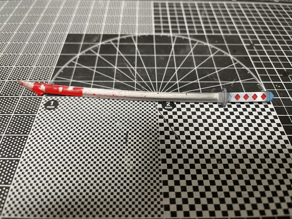 MSG日本刀を使用。刀身をミラークロームで塗装後塗料の攪拌棒で赤をドロッピング。その周りをエアブラシを使ったスパッタリングで飛び散ってる感じに塗装しました。割といい感じに垂れてくれて嬉しい。