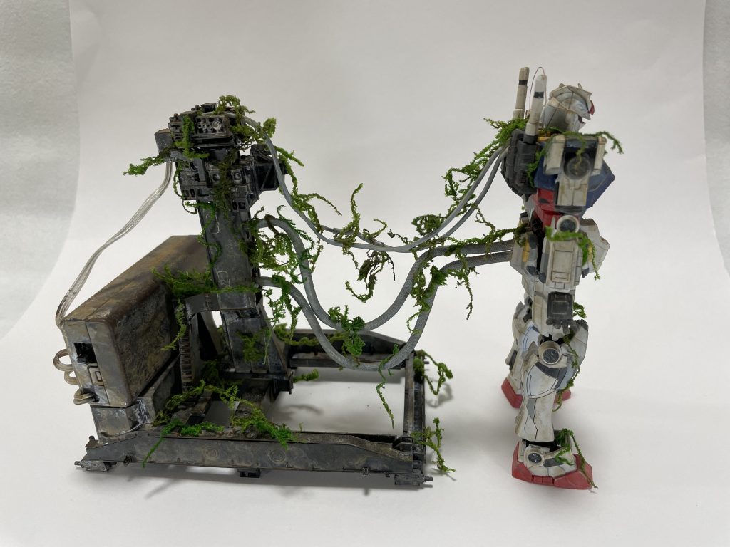 最後にガンダムの側面です。ケーブルでガンダムの支柱とつなげているのはエヴァリスペクトです。シン・エヴァがはやく公開されることを祈っています。支柱のうしろにあるのがLEDの電池ボックスで、もともと透明だったものにウェザリングをほどこして目立たないようにしています。中の電池を交換することもあるためグリーンモスはつけていません（ポロポロとれちゃうので）妄想設定の余談ですが、この横浜ガンダムは2号機で熱核エンジンのテスト用として作られたという妄想です。熱核エンジンの小型化がまだ不十分でガンダム内部に搭載できないため、支柱として外部に設置。ただ支柱としても不安定かつガンダムの動きを阻害するため、結局はケーブル接続としてガンダムと離された…という感じです。 最後まで読んでいただきありがとうございます！約１ヶ月で作成しましたが、色々なチャレンジも出来てとても楽しかったです。ぜひ横浜ガンダムを見に行った際はお土産にどうぞ(*´∀`*)