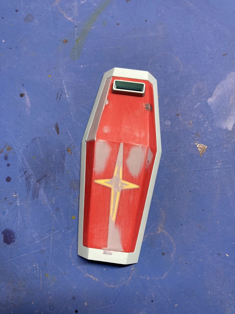 シールドの制作途中の写真連邦マークは元々あった黄色のパーツを逆にして接着し、隙間をひたすら瞬着、パテで埋めては削りました。シールド上部の突起は削り取るだけだと穴ができるので適当なランナーで塞ぎつつこちらも瞬着とパテで解決してます。目はプラ板で、クチバシはパテの削り出しにし、塗装後に接着してます。  