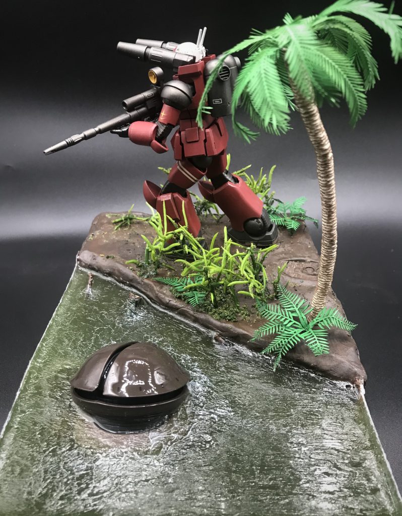 側面より。ヤシの木は100均のアレンジワイヤーを重ねてその上からタコ糸を巻き付けています。着色は水性ホビーカラーのマボガニーとウッドブラウン。ヤシの葉っぱは和巧さんのヤシの葉1/48を使用して、水性ホビーカラーのグリーンで着色。背の低い緑色の植物は100均で購入したものに緑と茶色のターフをまぶしています。シダ植物はグリーンスタッフワールドさんのシダ科の葉を使用し、グリーンに着色。