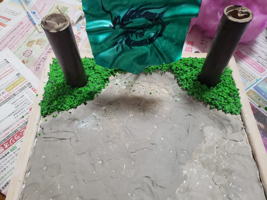 土台を作成、色付け後に紙パイプを使って幹の表現。樹皮の再現なんて高難度な事は出来そうにないので茶色く色塗りを行っただけで終わりました。幹の周辺を土手の様に少し段差をつけカラースポンジを二種類混ぜた物を貼りつけ、芝生を表現してみました。乾燥後に花の部分を紙パイプに差し込み完成しました。 まだまだ作りは荒いですが、１作目と言うことでこのままにしておこうと思います。 