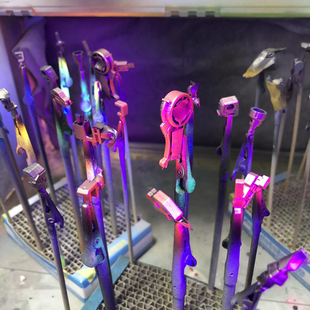 「エアテックス ブラックライトペイントルミネ 赤」を塗装中。無色透明なのにUVライトを当てると赤く光るすごいやつです。成型色や塗装でのトランザム表現に比べるとやや薄味ですが、ギミック重視という事で。塗料が元々希釈不要の薄さ、かつUVライトを当てないと塗った塗料が見えないので塗装作業が思ったより大変でした。アルコール系?なので重ね塗りには注意が必要。配色GN粒子を意識したキラキラ感を出そうとしています。白部: 白サフ→(G)パールシルバー→(G)クリアホワイト→ルミネ赤→(C)水性トップコート半光沢青部: グレーサフ→(C)コバルトブルー→(タミヤ)パールクリヤー→ルミネ赤→(C)水性トップコート半光沢赤部: グレーサフ→(C)モンザレッド→(タミヤ)パールクリヤー→ルミネ赤→(C)水性トップコート半光沢黄色部: グレーサフ→(G)ブラックEx→(G)スターブライトシルバー→(G)蛍光クリアー イエロー+レッド調色コンデンサ、GNソード改: (G)蛍光クリアーを調色、コンデンサ裏に銀テープ貼付