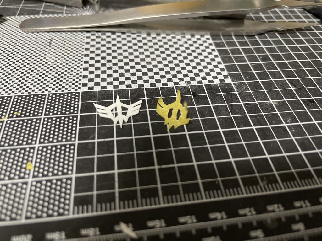 シールドのマーク。デカールの再販のタイミングで買い物行けないし探すの大変なのでマーキング塗装しました。普段は拾い画をマステに貼ってマーク切り抜いてるんですけど、思ったより上手くいかず、どうしていいかわからなくなったのでプラ板からマークを切り出してその上にマステを貼る→プラ板に沿ってテープを切り抜く、先に黄色く塗装して切り抜いたマークを貼った上から塗装してます。話題になってますけど、売ってないとか再販されないとかいうくだらない理由で無版権のデカール使うのやめましょう。工夫しましょう。ここに上げてもいけません。十字のマークはパテ埋めしてツートンで三連星カラーを詰め込みました。シールド一枚に何回塗り重ねたか…。マークは厚く吹くとマスキング剥がす時に塗装の端っこ持ってかれるんで薄めに拭きましょう。今回は若干歪かも。