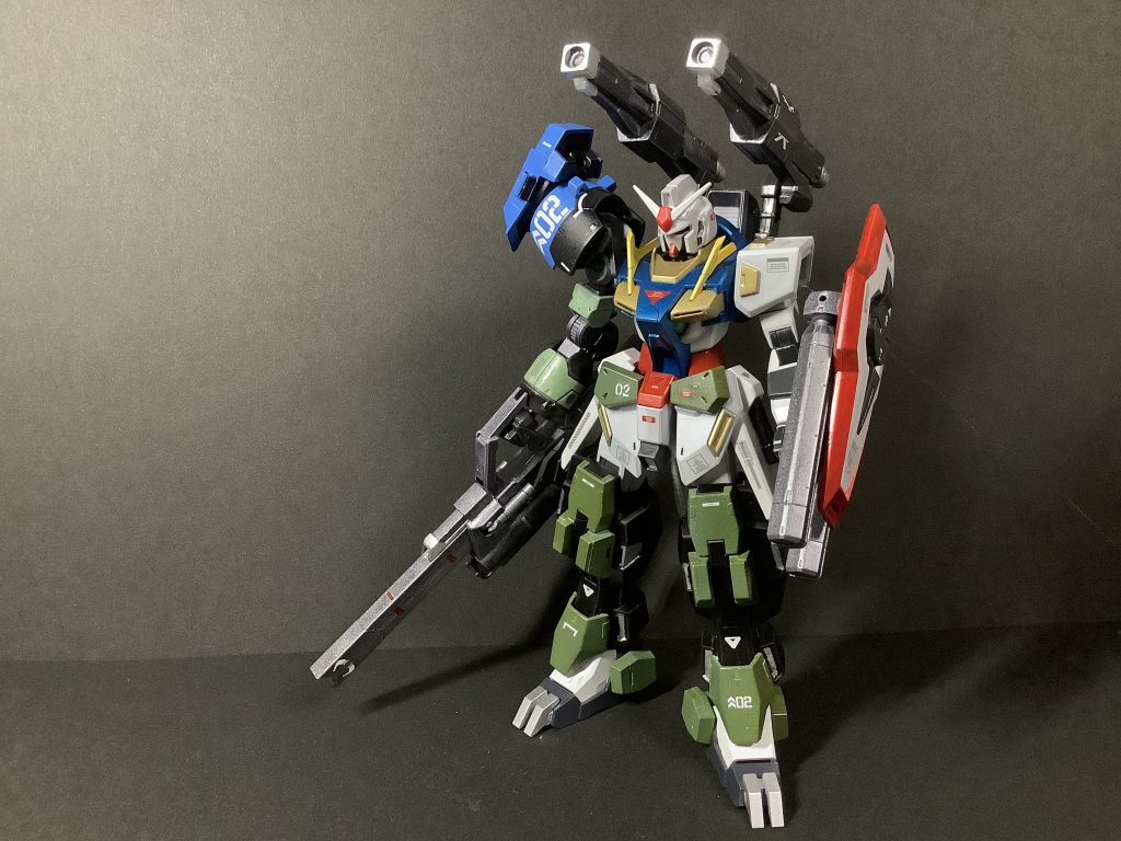 素立ち　正面主武装としては・GNメガランチャー・GNショルダーキャノン×2・GNシールドライフル左肩のGNドライブから直接GNフィールドを展開するため出力がかなり高く、GNZ系列より強力なフィールドを展開できます。同様にドライブと直結している左腕に装備されたGNメガランチャーは、トランザム時ヴァーチェと同等の最大火力を持っています。反面、オリジナルのGNドライブを搭載していてもなお粒子供給量が追いつかないため、各部に粒子貯蔵タンクやGNコンデンサーが強引に取り付けてあり、その影響でトランザムは使用できません。…あ、ちなみに各部のの『02』はver.2という意味です。ver.1は実践配備型。深い意味はないです（小声）