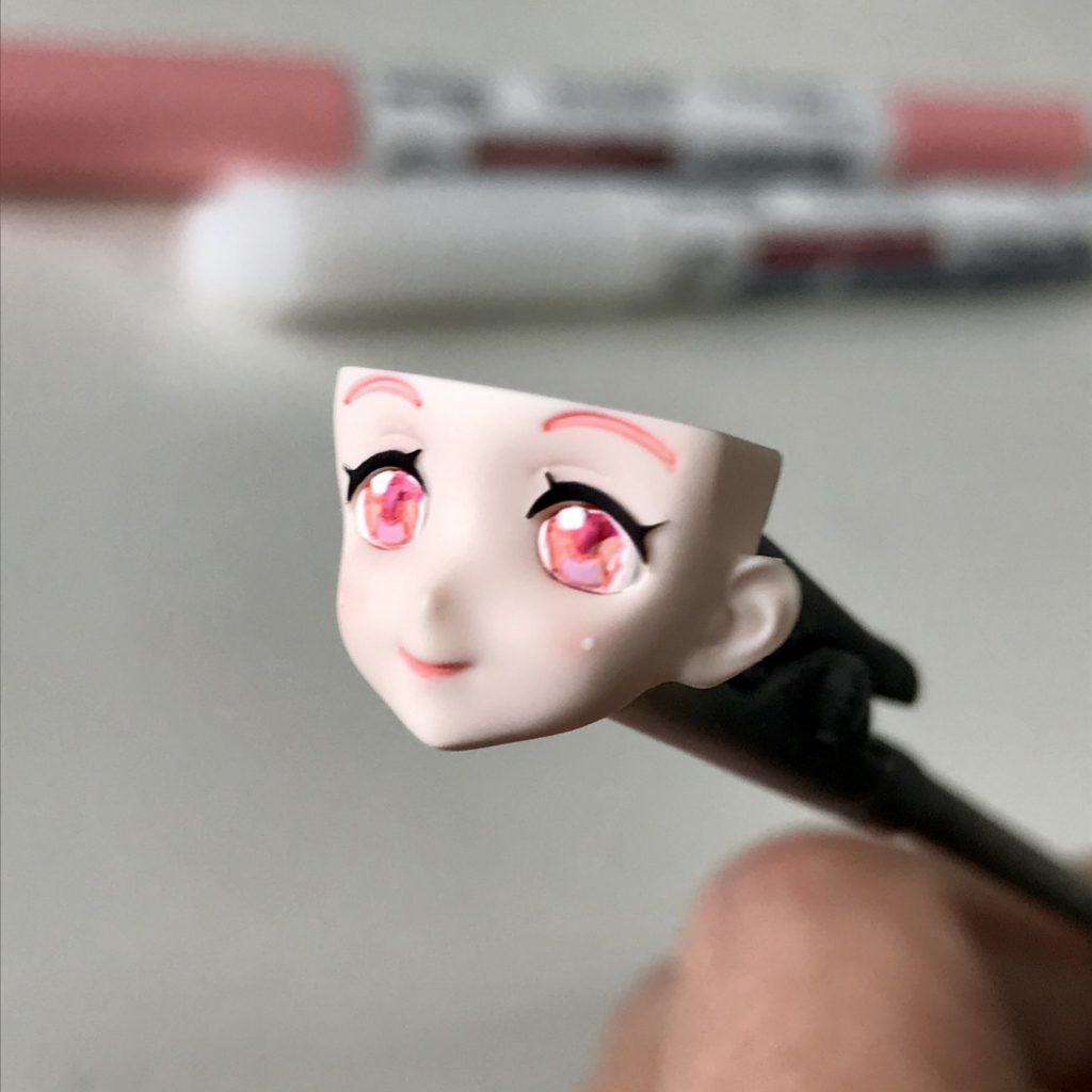 瞳は三色のピンクと白で塗りました。頬のピンクはいつもより強めにして、ハイライトも入れました。まつ毛と眉毛はリアルタッチマーカーで塗装です。