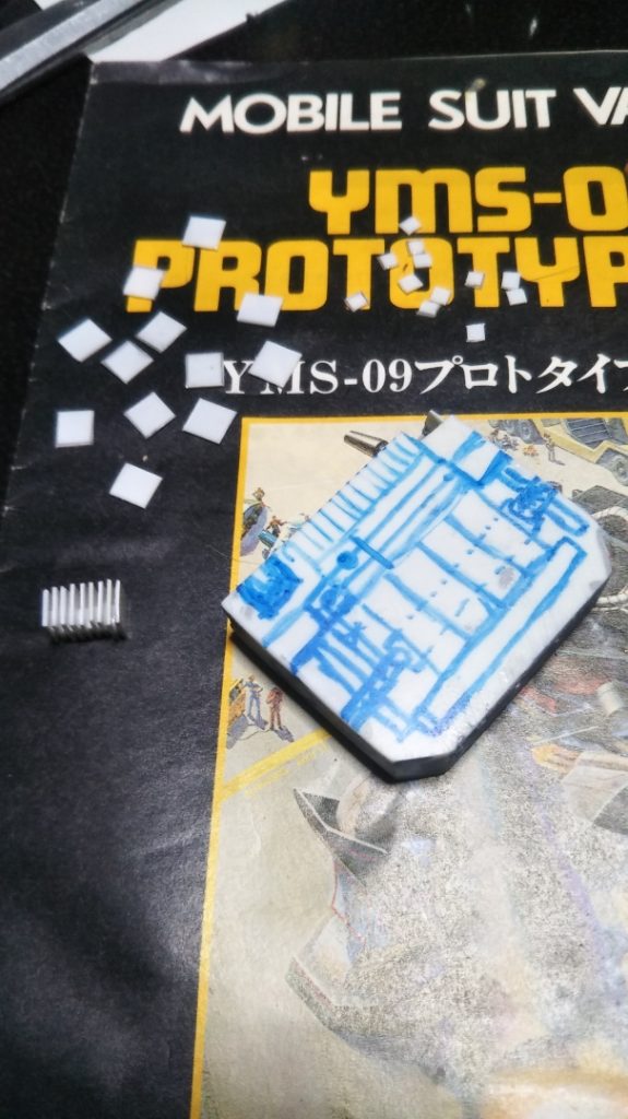 　バックパックの加工です。　元のデザインではバックパック上部にラジエターのようなディテールが確認できたので、大小2種類のプラ板を20枚ずつほど用意し、互い違いに貼り合わせて、いわゆる「しいたけモールド」的なモノを作ってみました。　ちなみに、バックパックの青い落書きはマッキーによる下書きです。