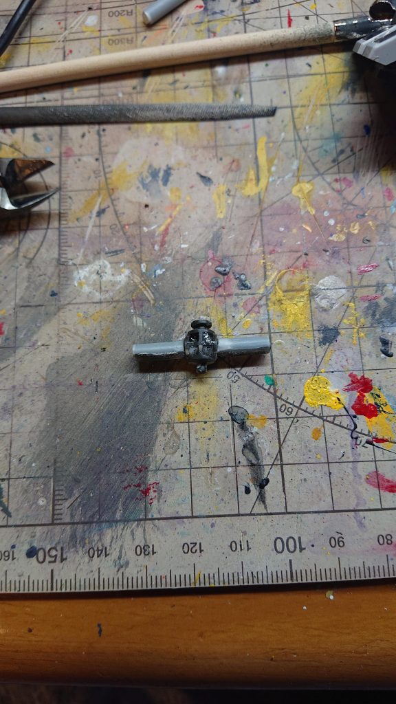 そして4mmのプラ棒の真ん中に2mmのドリルで穴を少し空けて先程通したプラ棒に取り付けますその後瞬間接着剤で接着しますしかしこの状態だとパーツを軸に通しても緩みがでてしまうのでキツくする為に軸にパテ型の接着剤を適量付けます最後に瞬着硬化スプレーを吹き掛け軸のパテをヤスリで削って軸のサイズを調整すれば完成です